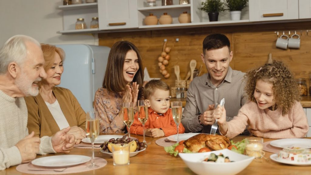 A joyful family gathering around a table for a Thanksgiving feast indoors.